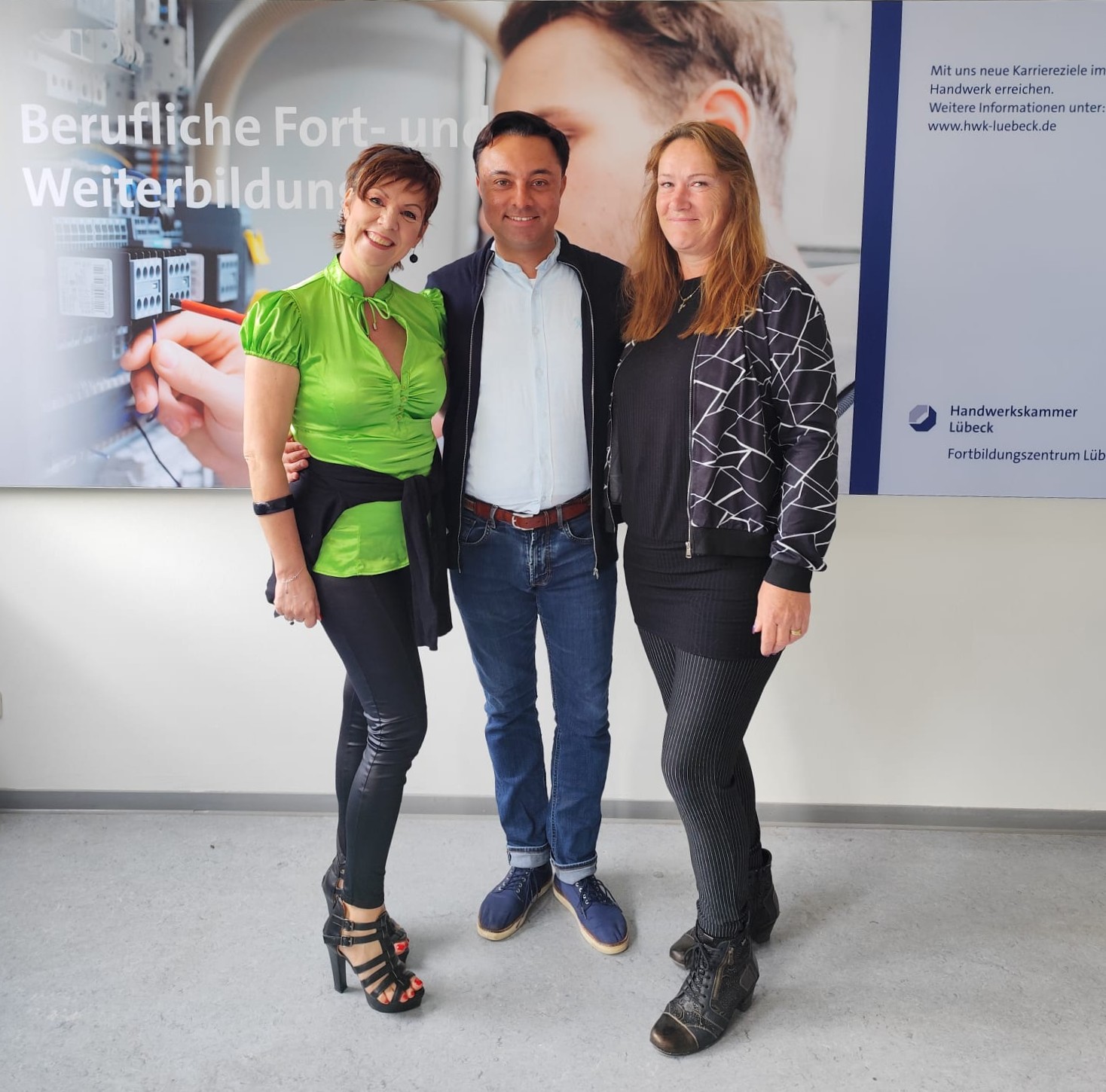 KI generiert: Drei Personen stehen lächelnd vor einem Plakat zur beruflichen Fort- und Weiterbildung.
