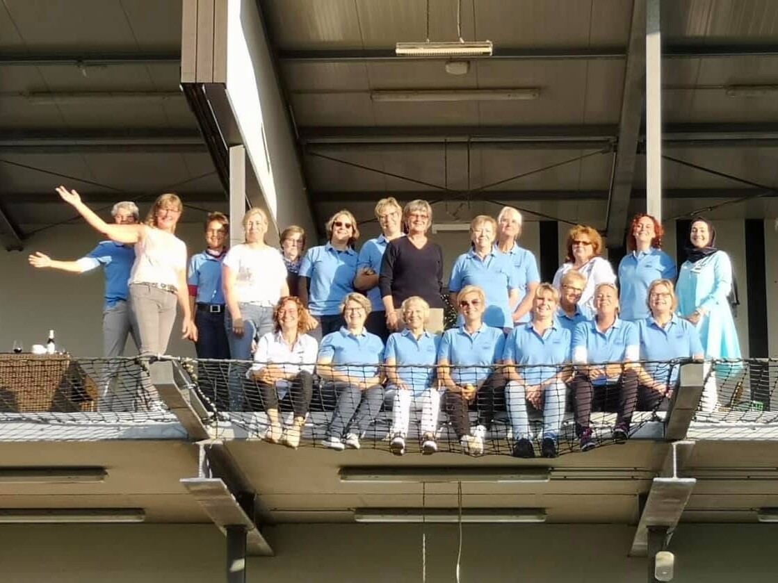 KI generiert: Eine Gruppe von Personen posiert zusammen für ein Foto auf einem Balkon oder einer Plattform.