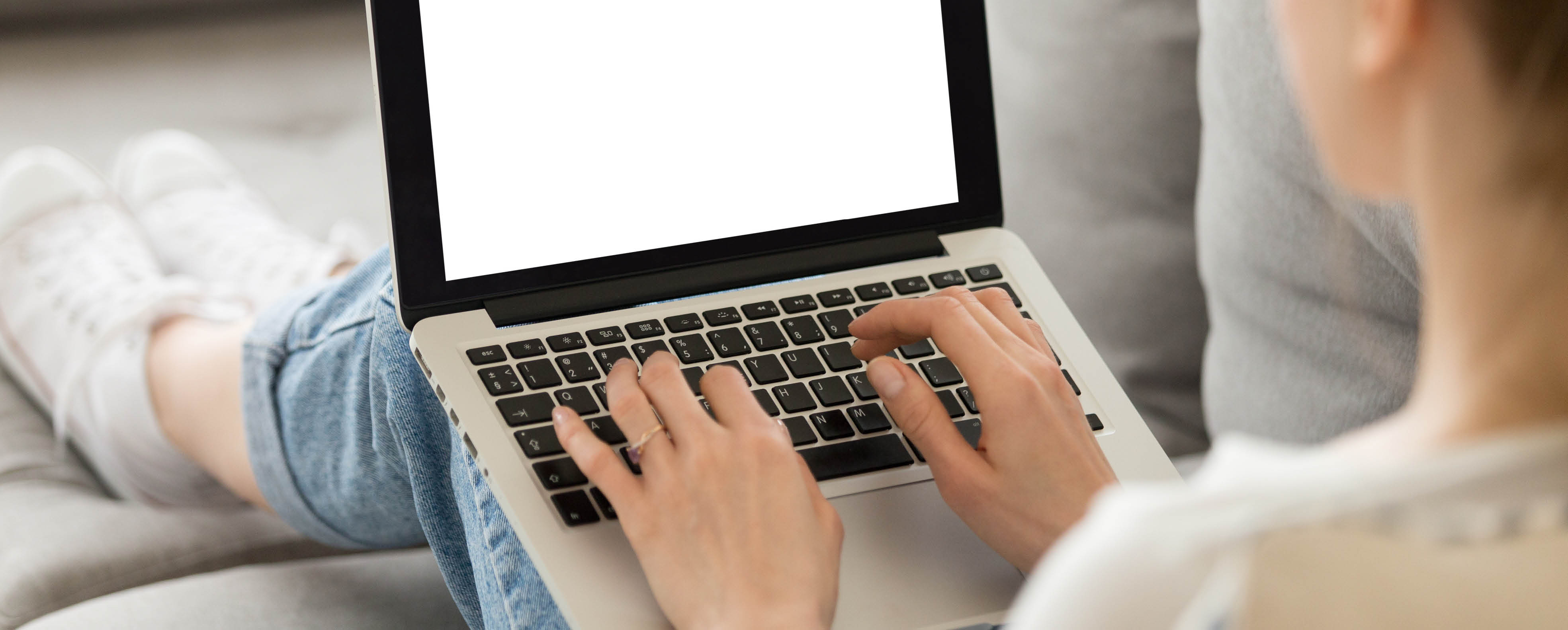 Frau arbeitet mit Laptop auf dem Schoß Frau arbeitet mit Laptop auf dem Schoß