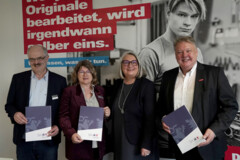 KI generiert: Das Bild zeigt vier Personen, die vor einem Plakat posieren und jeweils Dokumente in der Hand halten.