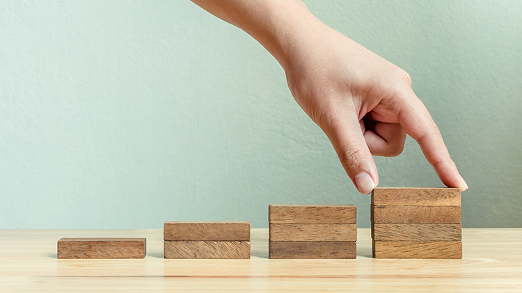 Hand baut mit Holzblöcken verschieden große Stufen